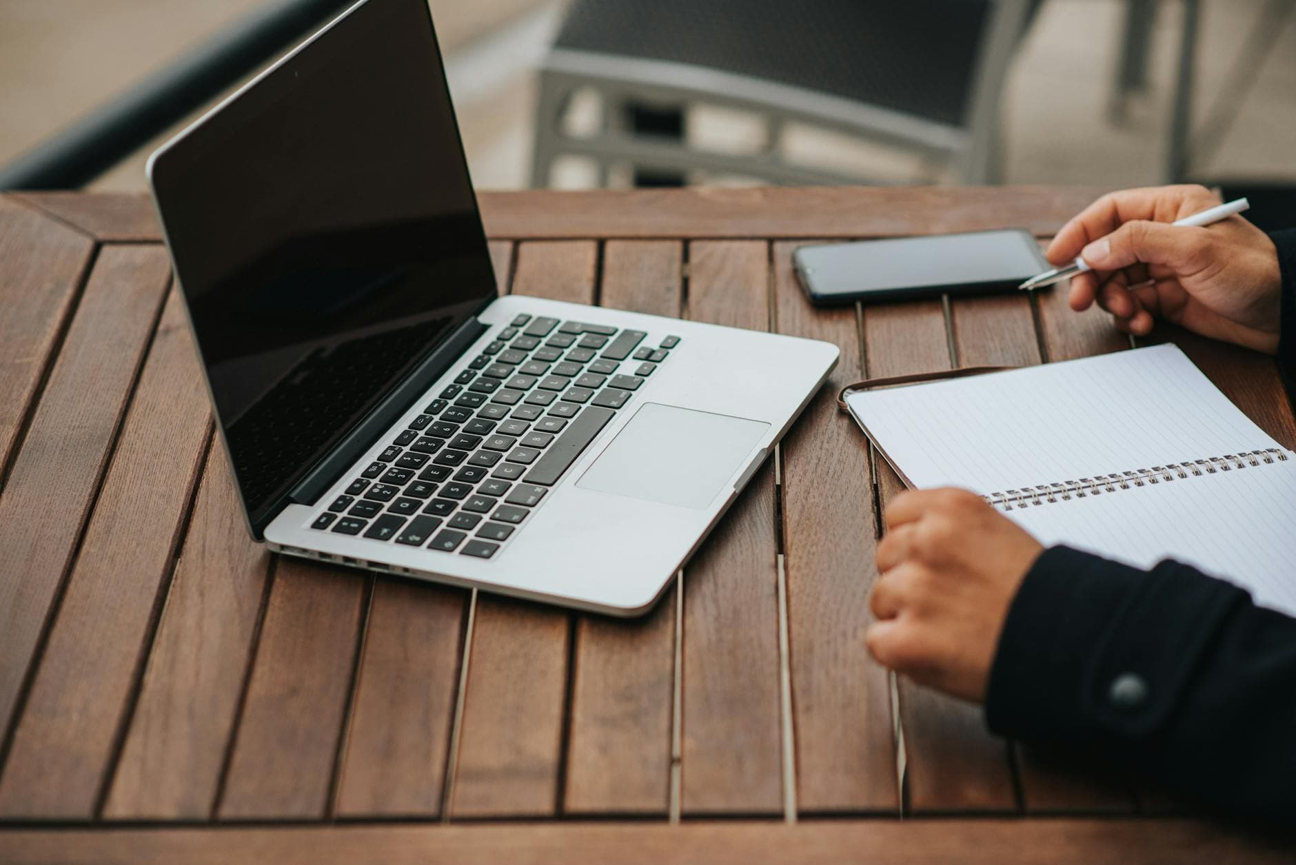 Focused learner writing notes beside a laptop